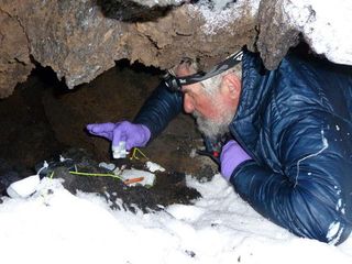 Biologist Hubert Staudigel tends to an experiment in an Antarctic ice cave.