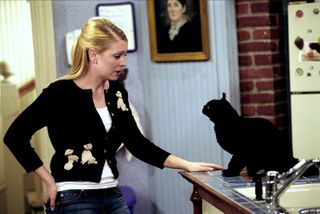 MELISSA JOAN HART as sabrina talking to her cat salem as he sits on a counter top in sabrina the teenaged witch