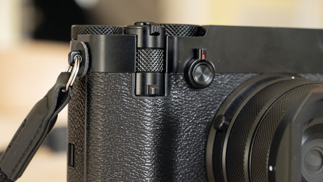 All-black Fujifilm GFX100RF rangefinder-style camera on a wooden table