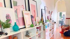 Knowing entryway decor mistakes to avoid is very useful. Here is an entryway with shelves filled with colorful decor and wall art, white walls, and wooden flooring