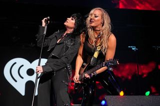 A picture of Nita Strauss and Demi Lovato performing on stage