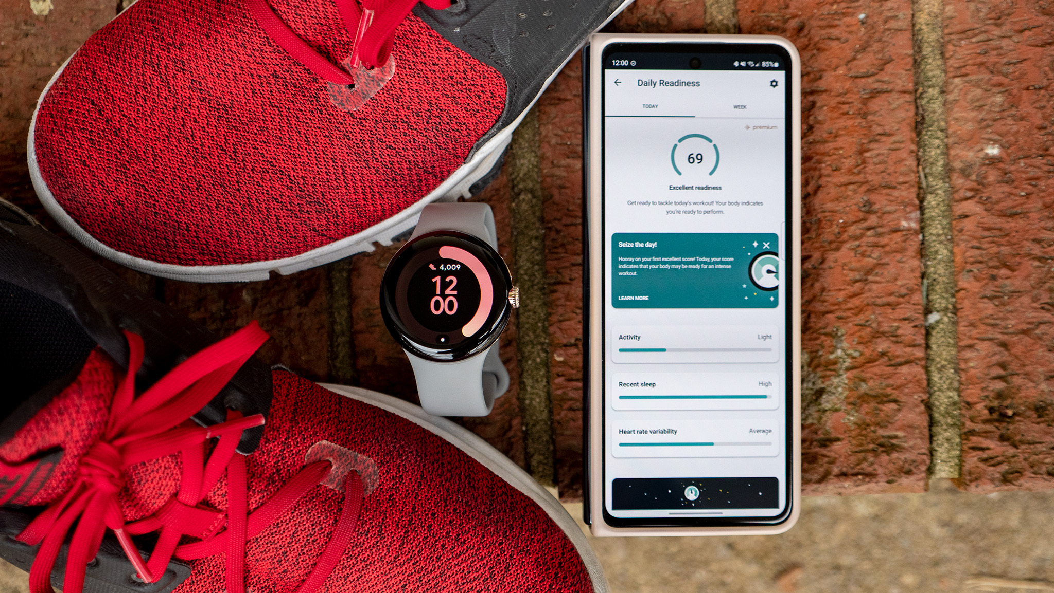Google Pixel Watch поруч із телефоном Android, який показує щоденну оцінку готовності Fitbit.