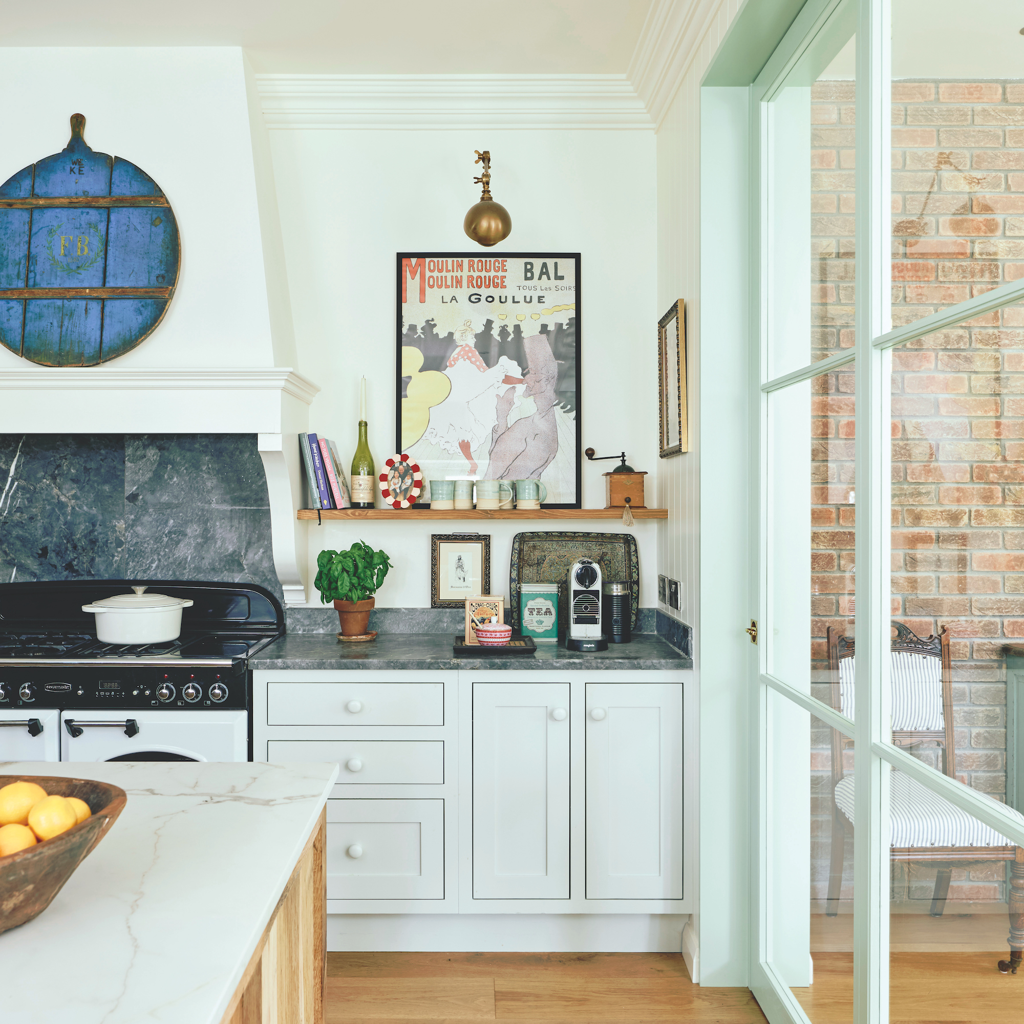 kitchen with white wooden units and white range cooker and vintage prints on wall