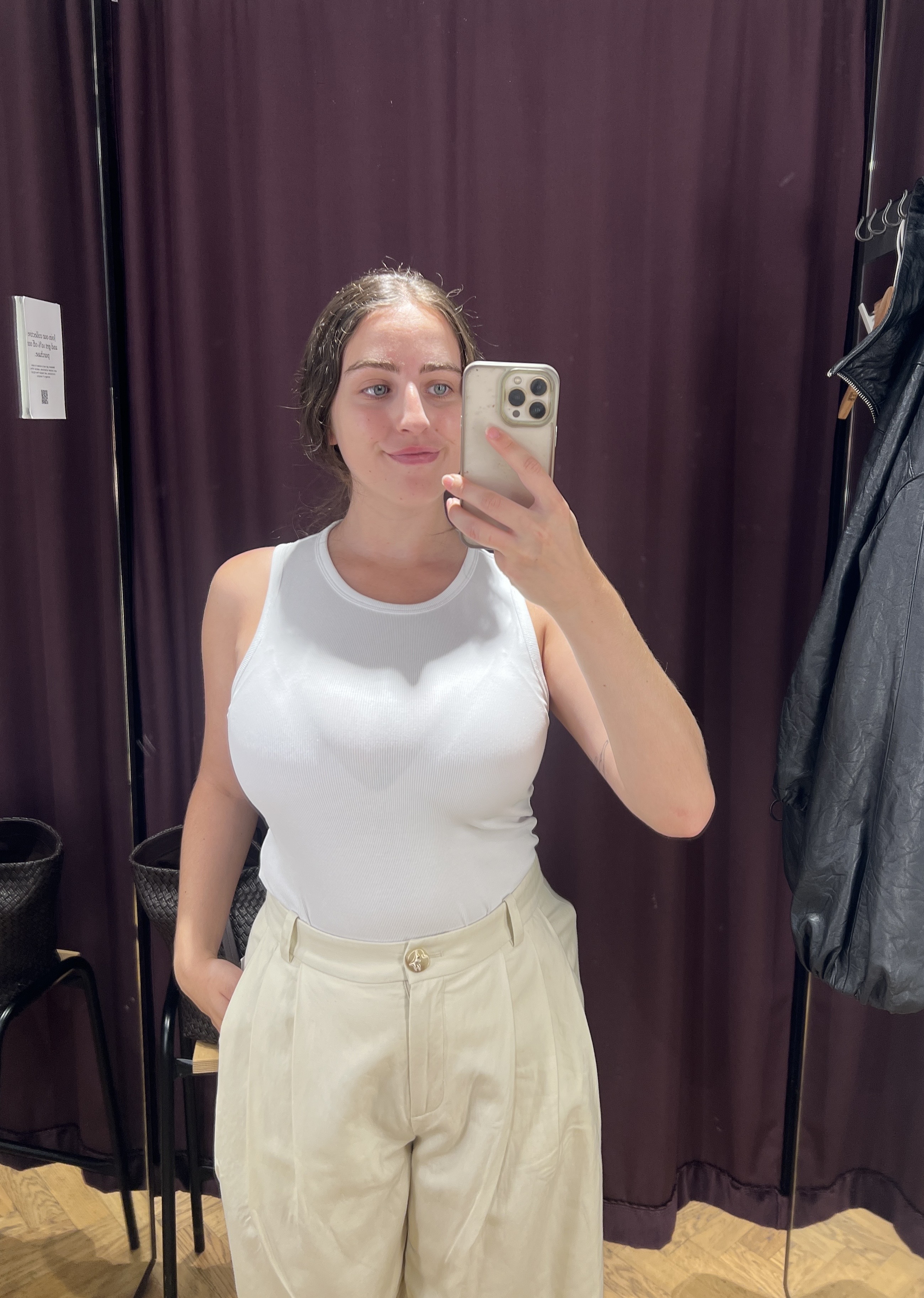 An image ofBest Knockoff Luxury Clothing
's Ava Gilchrist wearing an 
Other Stories white tank top with pleated trousers.