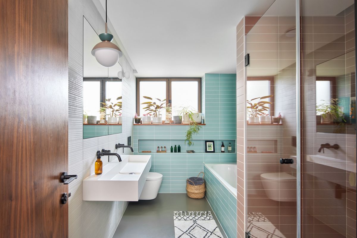 A bathroom with an 1960s aesthetic with blue and pink subway tiles, a bath and a glass shower enclosure