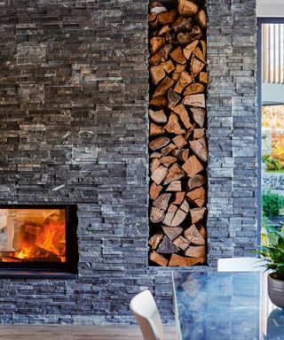dining room with grey stone wall and wooden design pillar and fire place
