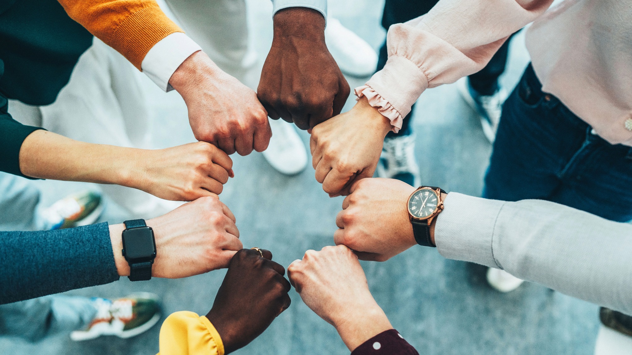 A close-up of multiple hands stacked together in a gesture of unity and collaboration. T