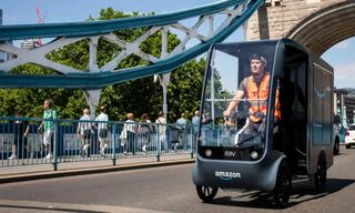 Amazon delivery driver cycling across a bridge in London