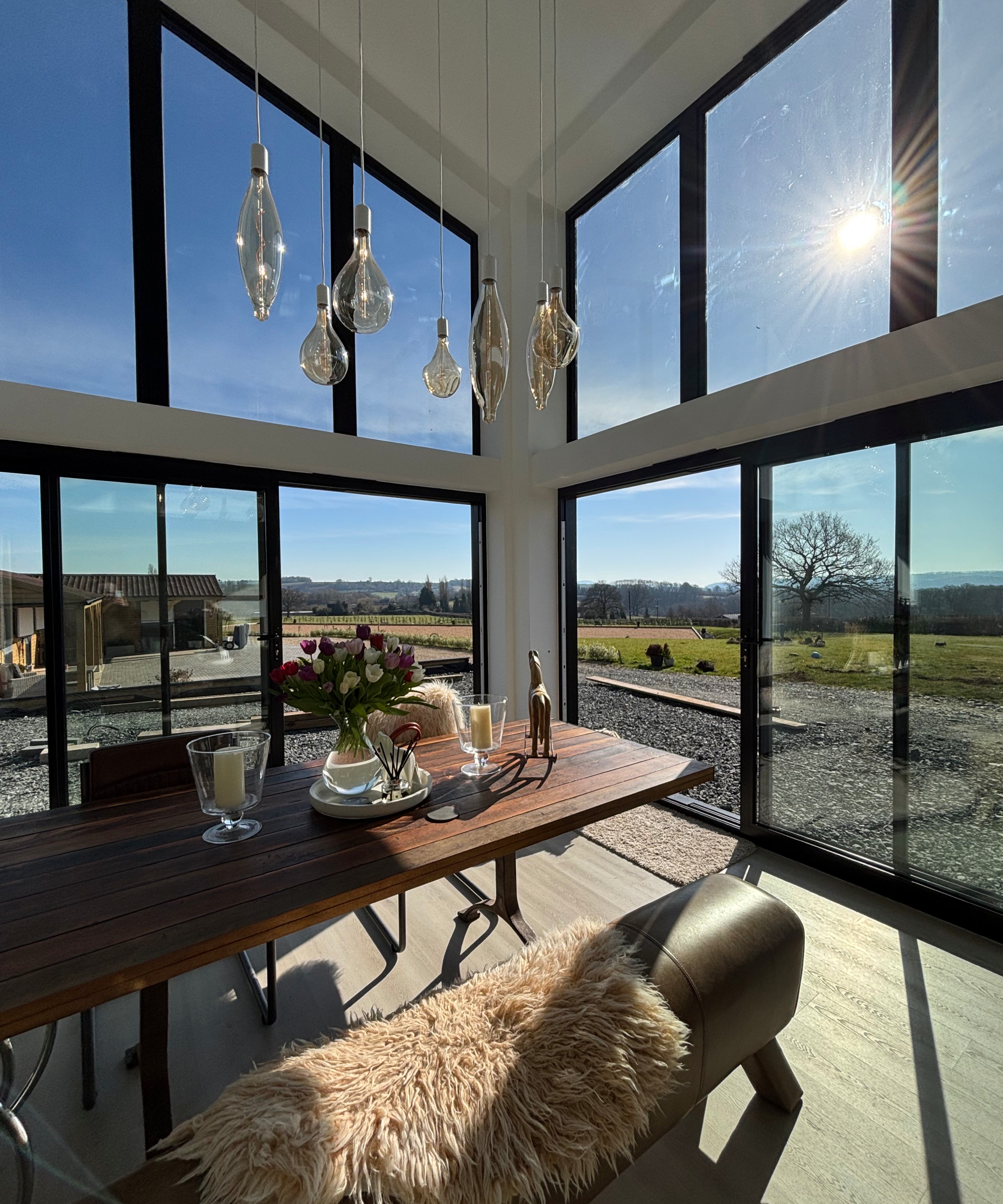 inside double height dining area with large glazed black framed sliding patio doors and large windows above