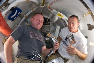 A short time before they donned spacesuits for a spacewalk, NASA astronauts Michael Fincke (left) and Andrew Feustel, both STS-134 mission specialists, are seen eating breakfast snacks onboard the International Space Station (ISS) on May 22, 2011 during Flight Day 7 of their 16-day mission.