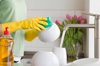 Person wearing rubber gloves doing the washing up