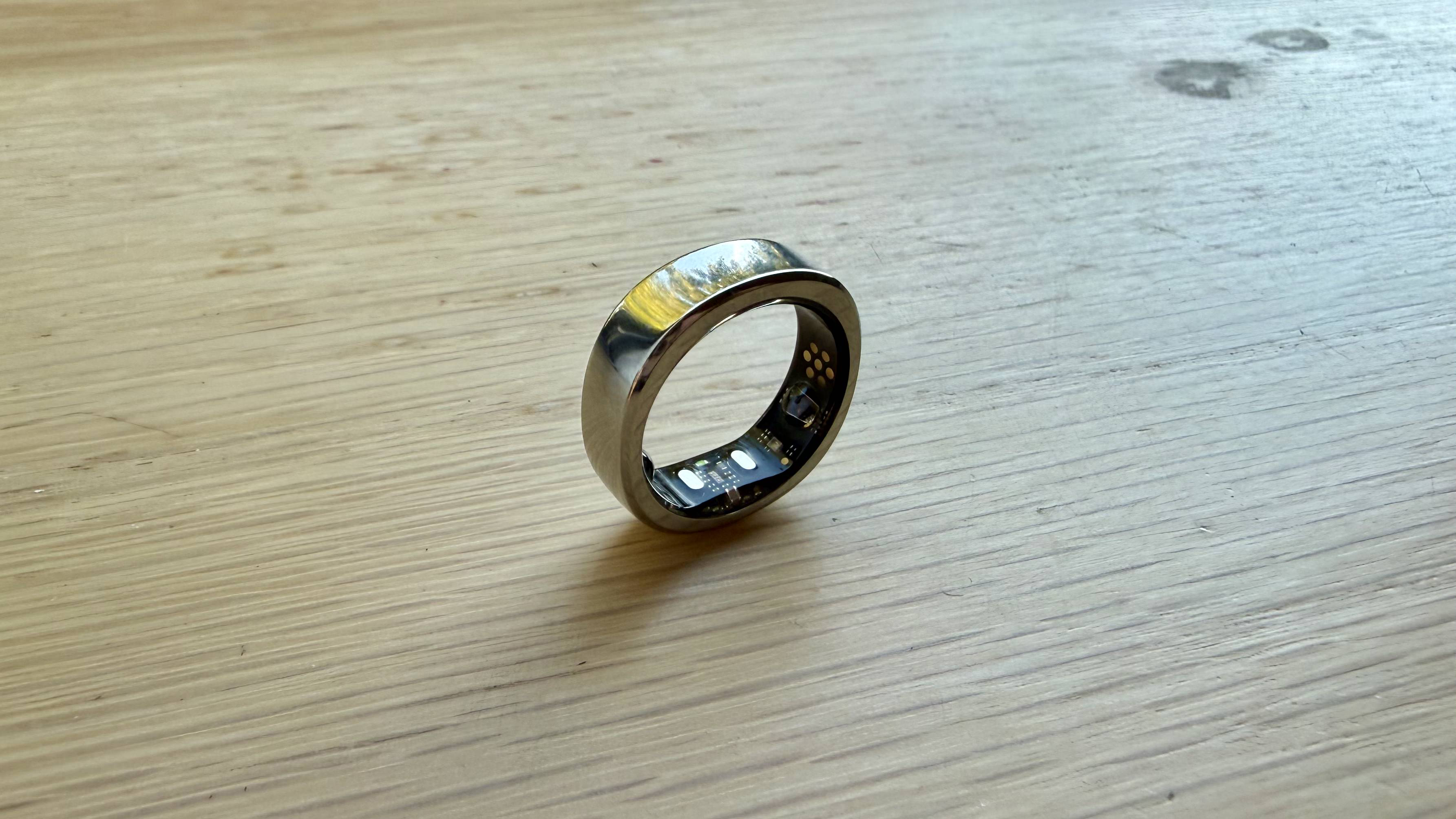 The RingConn Gen 3 in silver pictured balancing on its edge on a wooden surface