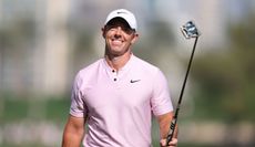 Rory McIlroy raises his putter in the air whilst smiling following his eagle putt on the 18th hole in Dubai