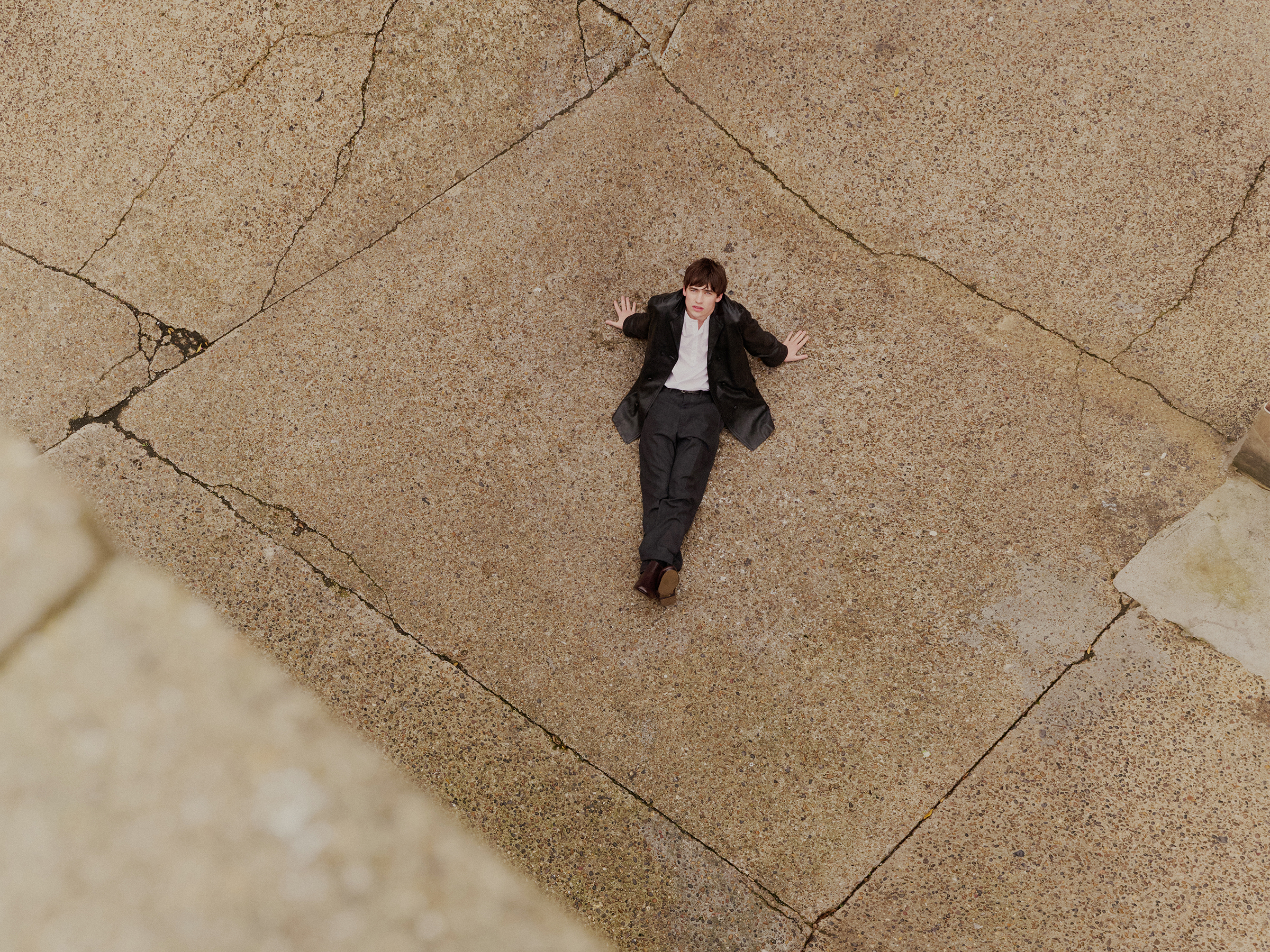 Spike Fearn is shot from above as he sits on concrete and looks up at the camera.
