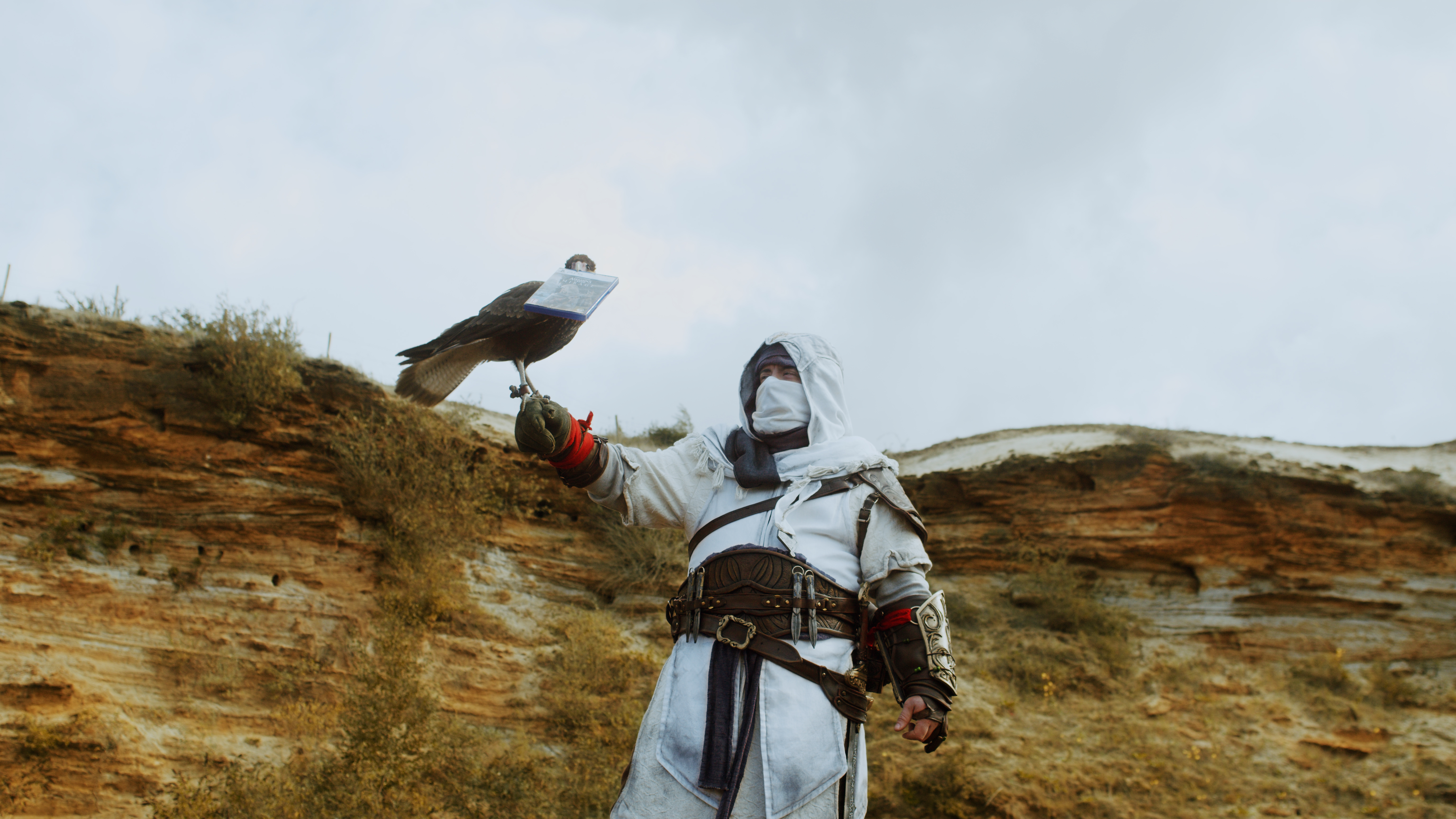 A man with a bird holding a copy of Assassin's Creed.
