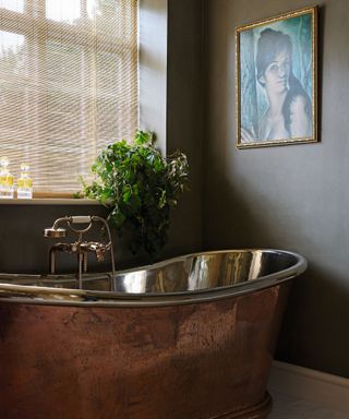 bathroom with black walls, artwork and copper bath tub