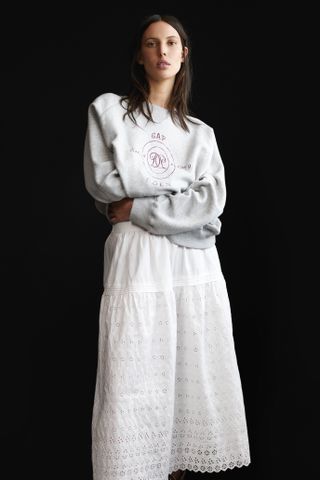 Ruby Aldridge wears a white eyelet skirt and logo sweatshirt in a guide to the gap x doen collaboration