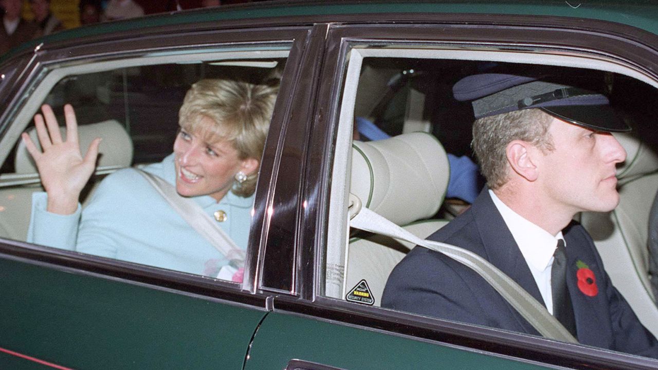 Princess Diana wears a baby blue jacket and waves from a green car being driven by her former chauffeur, Steve Davies