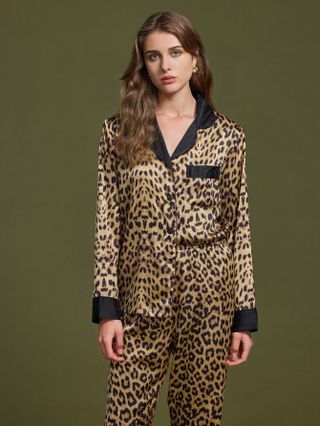 Woman wearing leopard-printed silk pajamas against green background