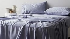 Sateen sheets on a bed against a white wall.