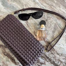 The Miu Miu Miutine perfume bottle on a marble table