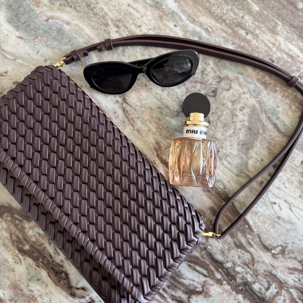 The Miu Miu Miutine perfume bottle on a marble table