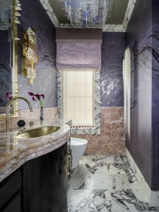 A grand purple bathroom featuring marble and gold