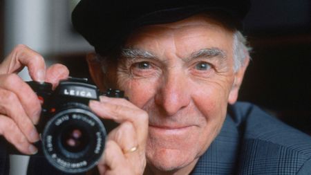 Portrait of photographer Robert Doisneau holding a camera.