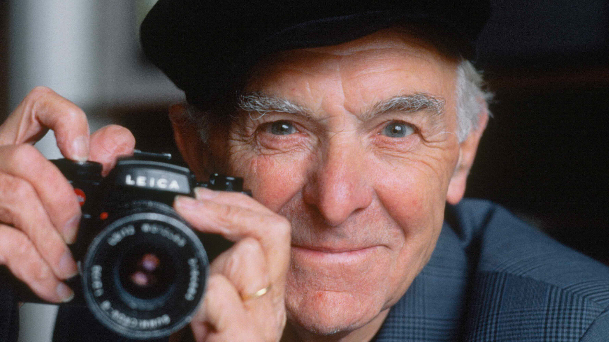 Portrait of photographer Robert Doisneau holding a camera.
