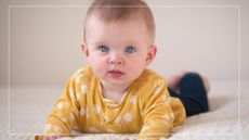When do babies start rolling over? A baby in a yellow top lays on her stomach pushing herself up.