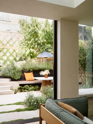 Patio area with pavers interspersed with sections of grass, built in seating and wooden square table