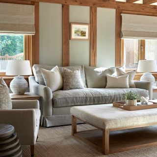 A greige-painted living room with wooden accents and a grey sofa