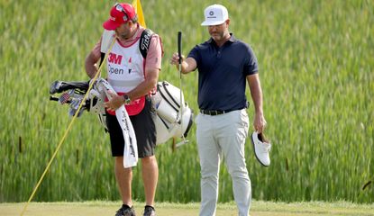 Piercy lines up a putt whilst holding his golf shoes