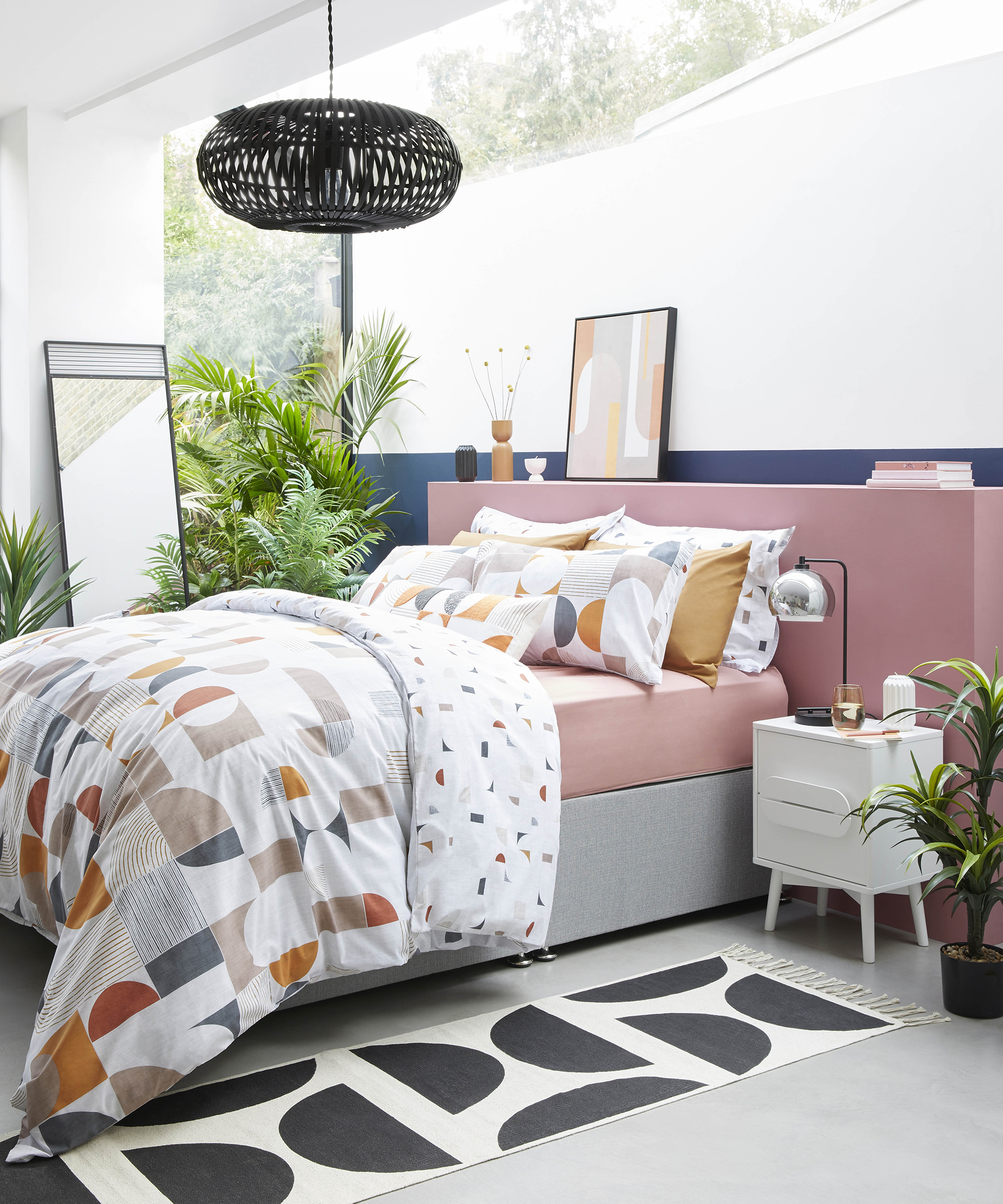 Pink bed with geometric duvet and rug by Dunelm