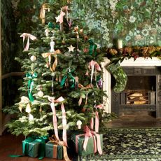 A bow-decorated Christmas tree next to a fireplace