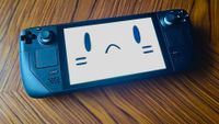 Steam Deck LCD on woodgrain table with sad face on screen.