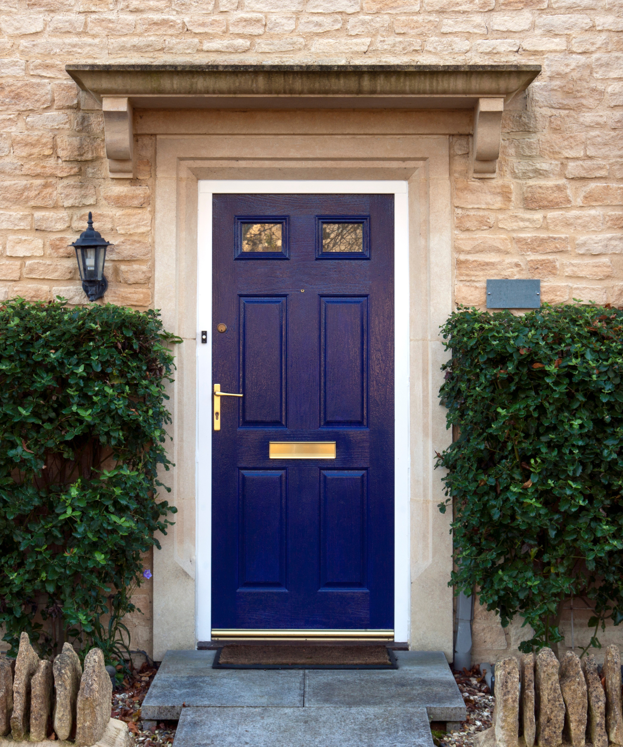 stone canopy above blue painted front door wit black lantern style porch light to one side