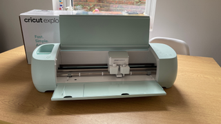 The best vinyl cutter machines; a mint green craft machine on a wooden table, its lid open and the box it came in