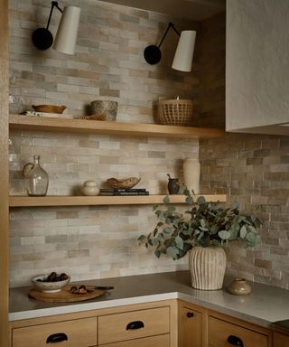 A corner of a spanish-style kitchen with wooden open shelving displaying decor and kitchenware