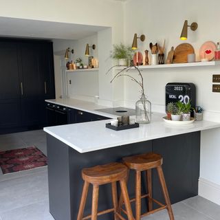 Breakfast bar in a dark grey kitchen with white worktops and open shelf