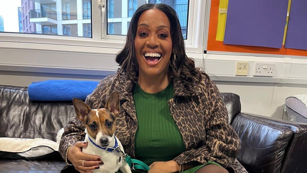 Alison in a green top and leopard print jacket cuddling a Jack Russell on a sofa 