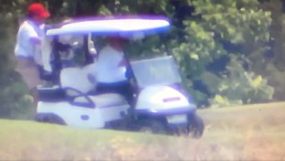 Trump driving golf cart with caddy