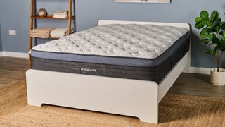 The Helix Midnight Luxe mattress placed on a white wooden bedframe, photographed in our blue coloured Testing Lab
