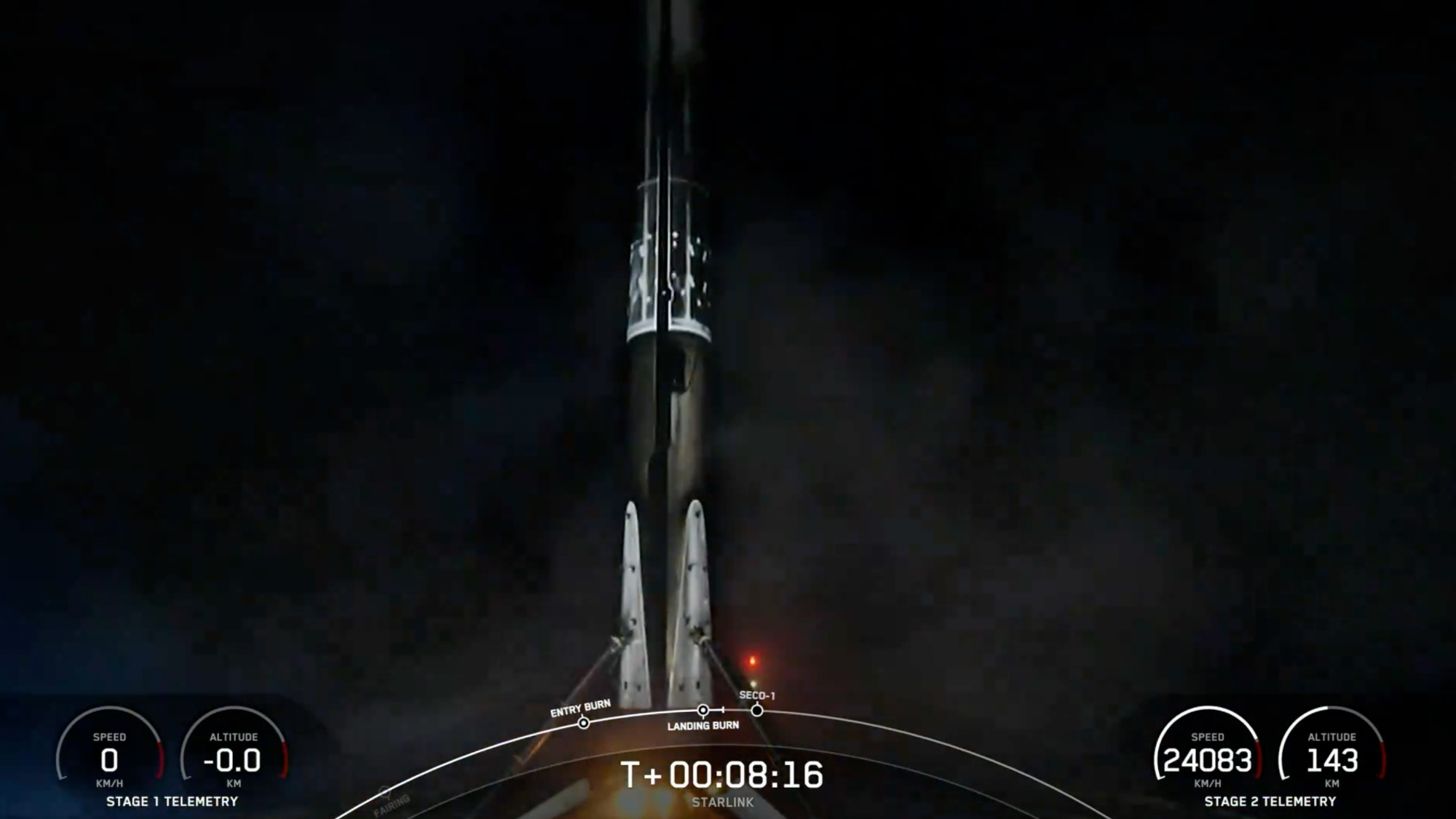 A black and white spacex falcon 9 rocket first stage sits on the deck of a ship at sea at night.