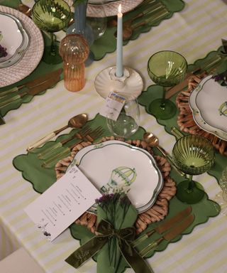 Green spring tablescape with scalloped placemats, striped tablecloth, rattan placemats and china plates