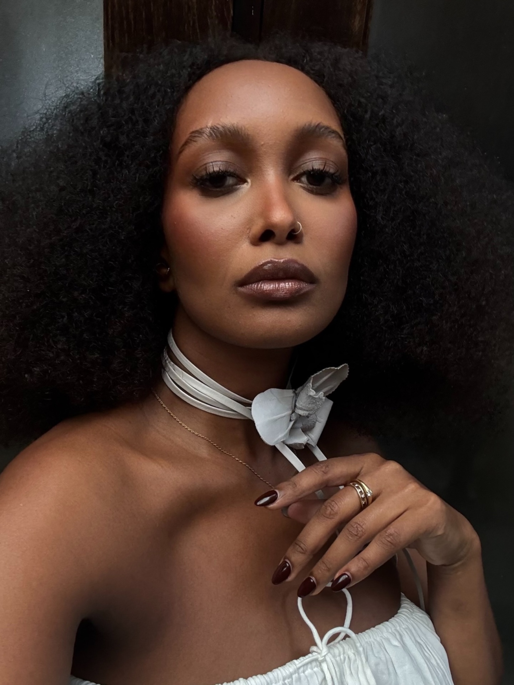 Mona Mali with full, natural curls and bronzed makeup
