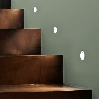 Recessed wall lights on grey wall next to wooden staircase