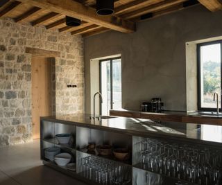 A Tuscan kitchen with rustic exposed brick walls and terracotta tile floors. The kitchen is a stark contrast, featuring a stainless steel island and contemporary appliances
