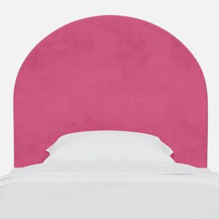 A curved pink headboard with white bedding