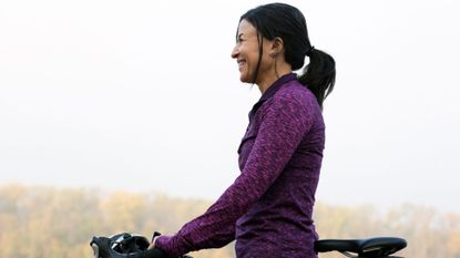 Woman doing cycling as a workout in forest smiling